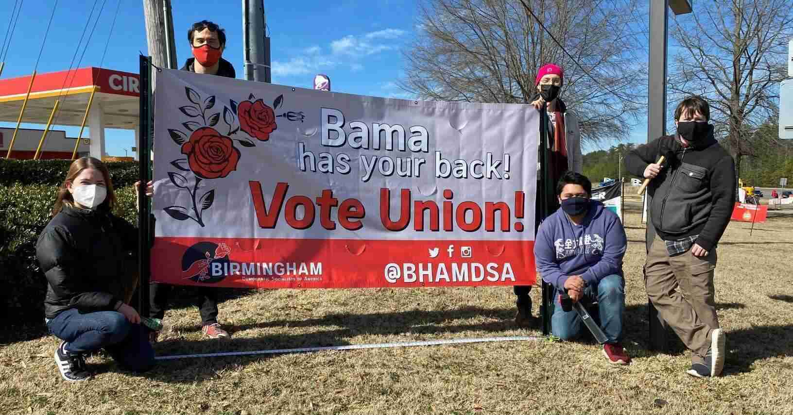 Several Birmingham DSA members standing holding a Vote Unition sign
